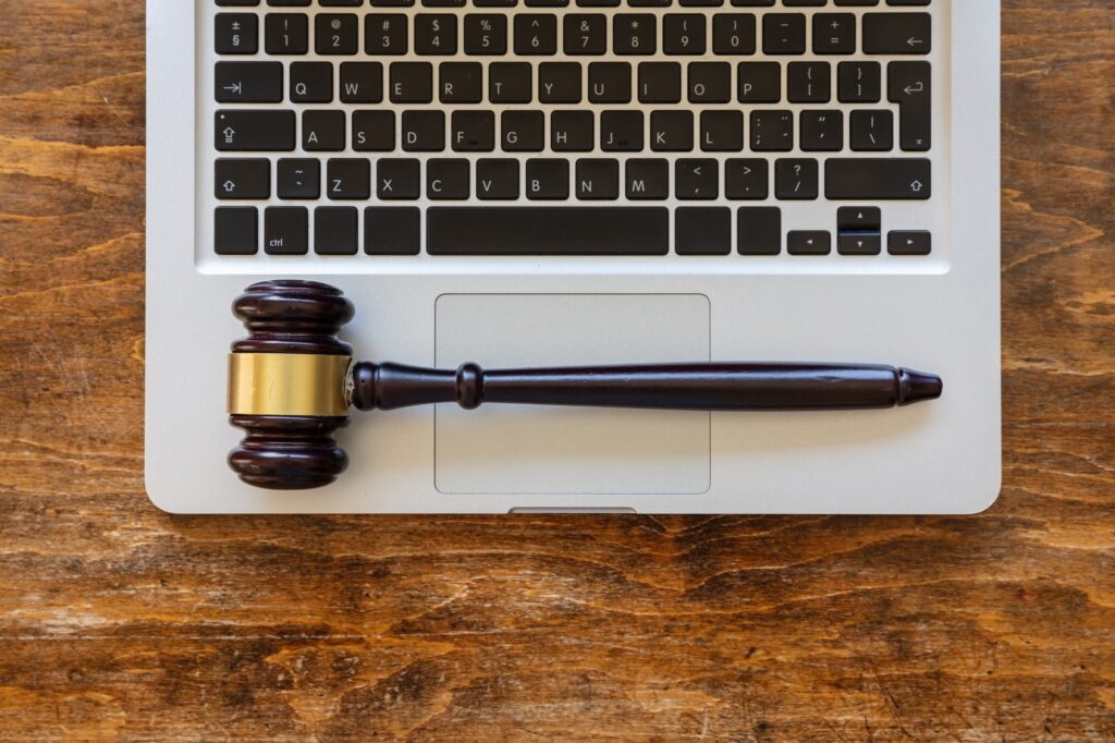 Judge gavel on a laptop, wooden background, top view. Online auction concept