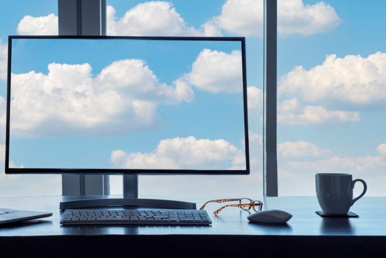 Conceptual cloud computing desk with computer, keyboard, mouse, eyeglasses and coffee.