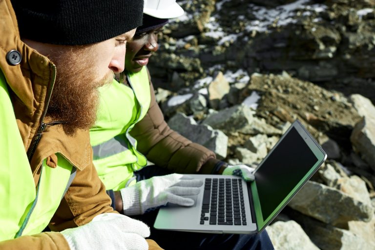 Two Workers Using Laptop on Excavation Site